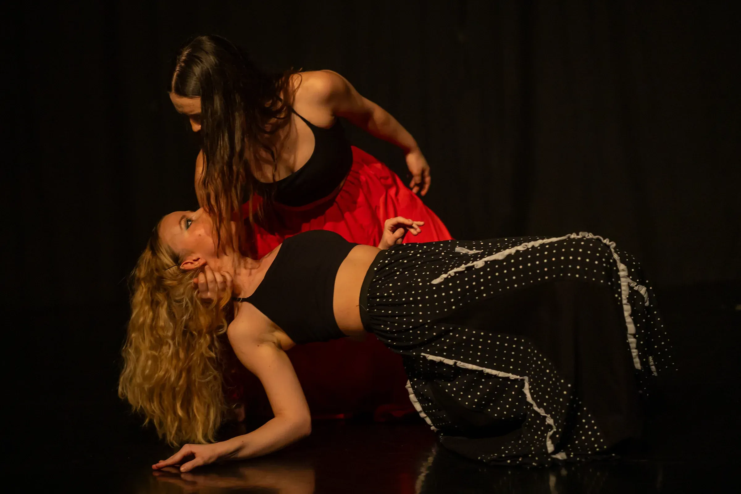 Floor duet: Lucie Marcellin arching back, supported by a dancer in a red skirt