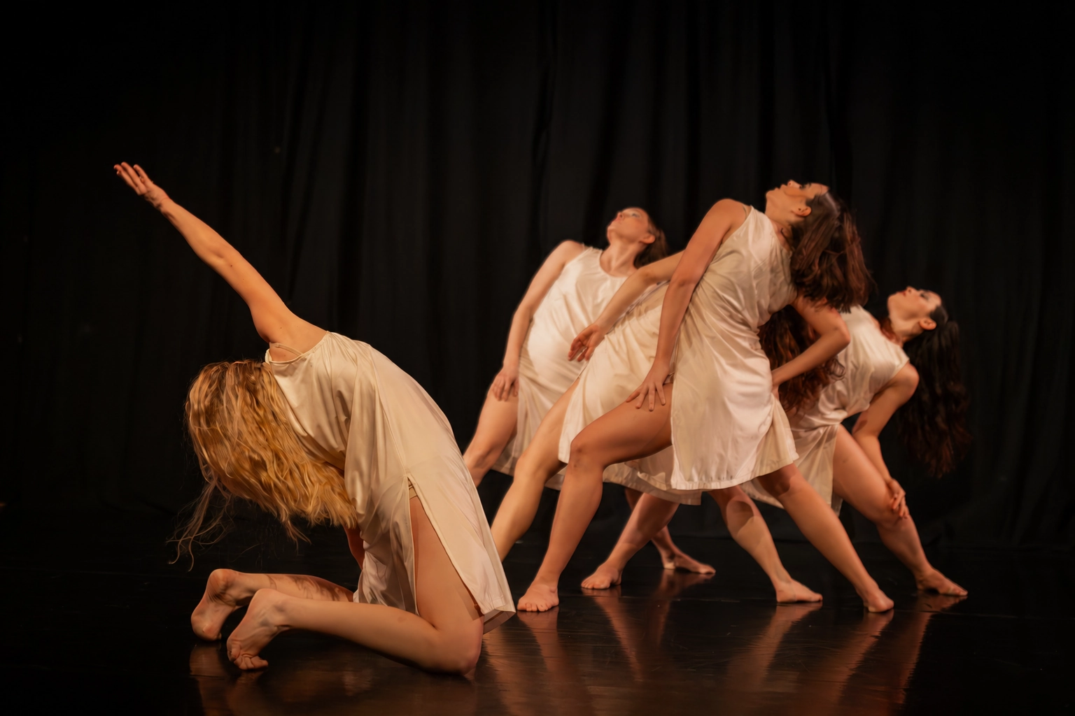 Lucie Marcellin and four dancers in pale dresses, arching against a black backdrop