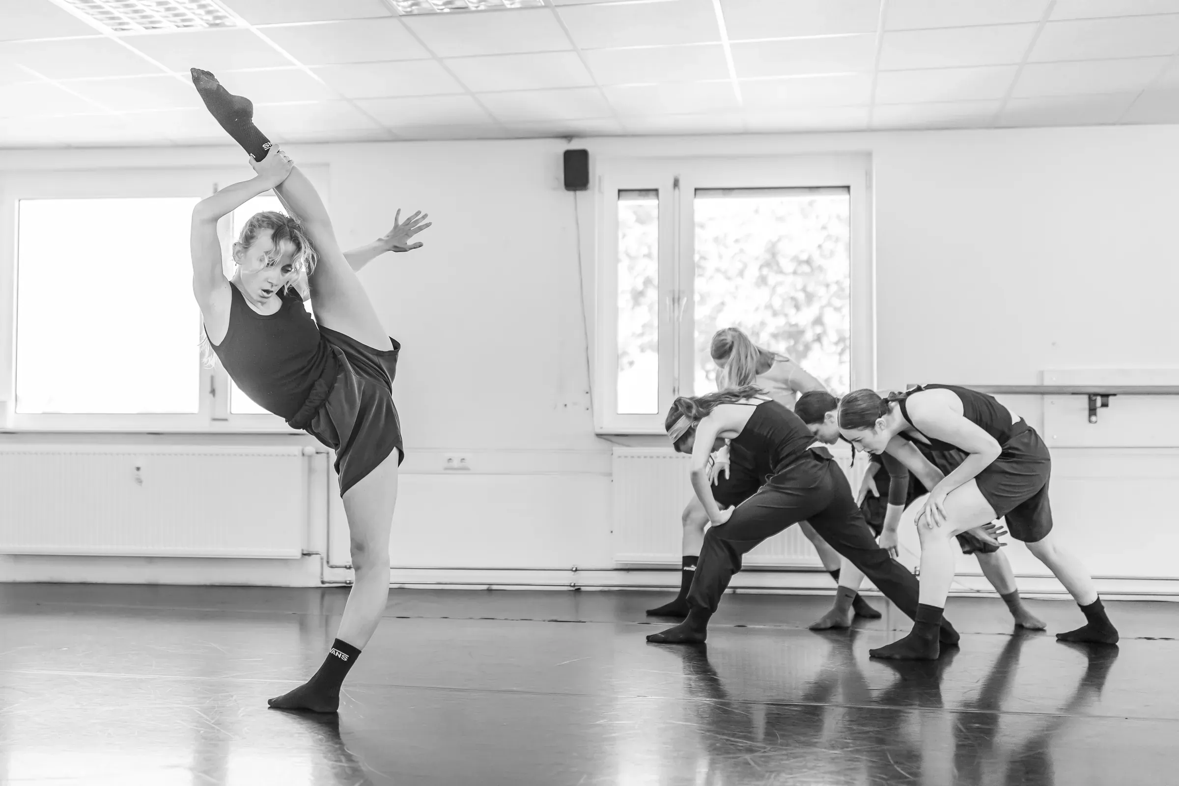 Lucie Marcellin with her leg extended overhead during a company rehearsal (black and white)