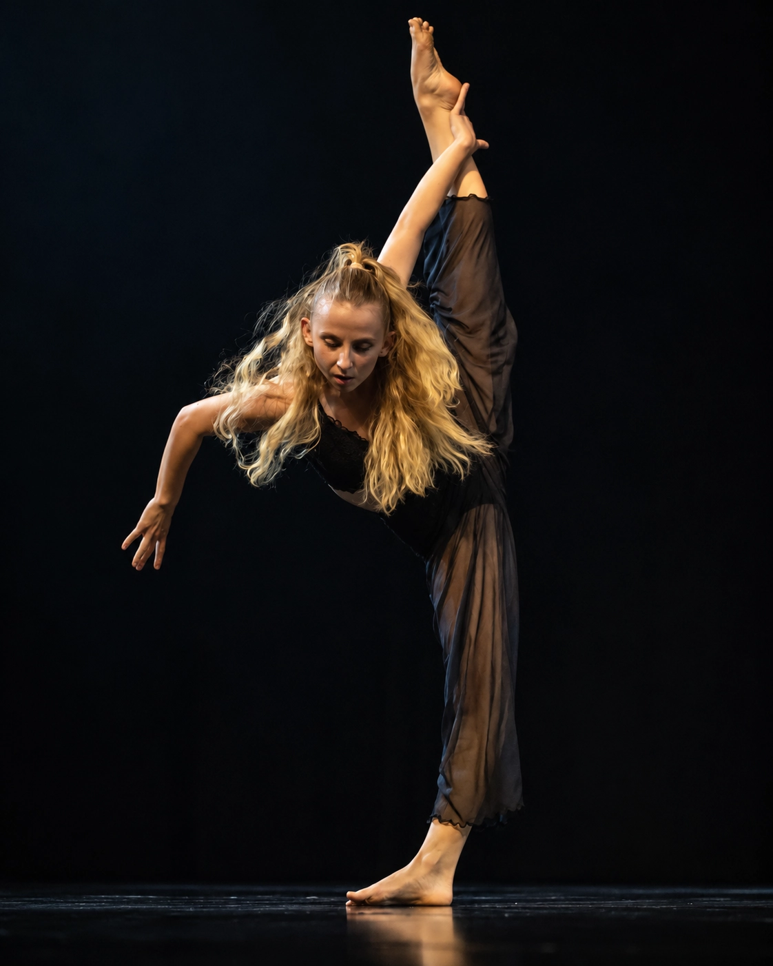 Lucie Marcellin performing a solo on stage, leg extended vertically, hair in motion